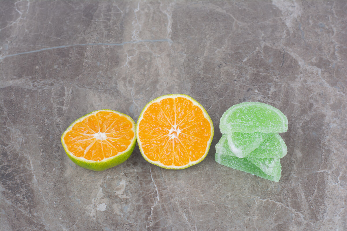 果冻新鲜的橘子片和甜甜的果酱放在大理石背景上新鲜糖美味