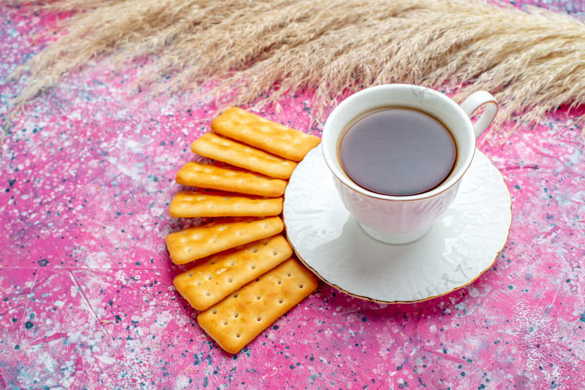 杯子在粉红色的桌子上放一杯茶和饼干茶茶碟杯子
