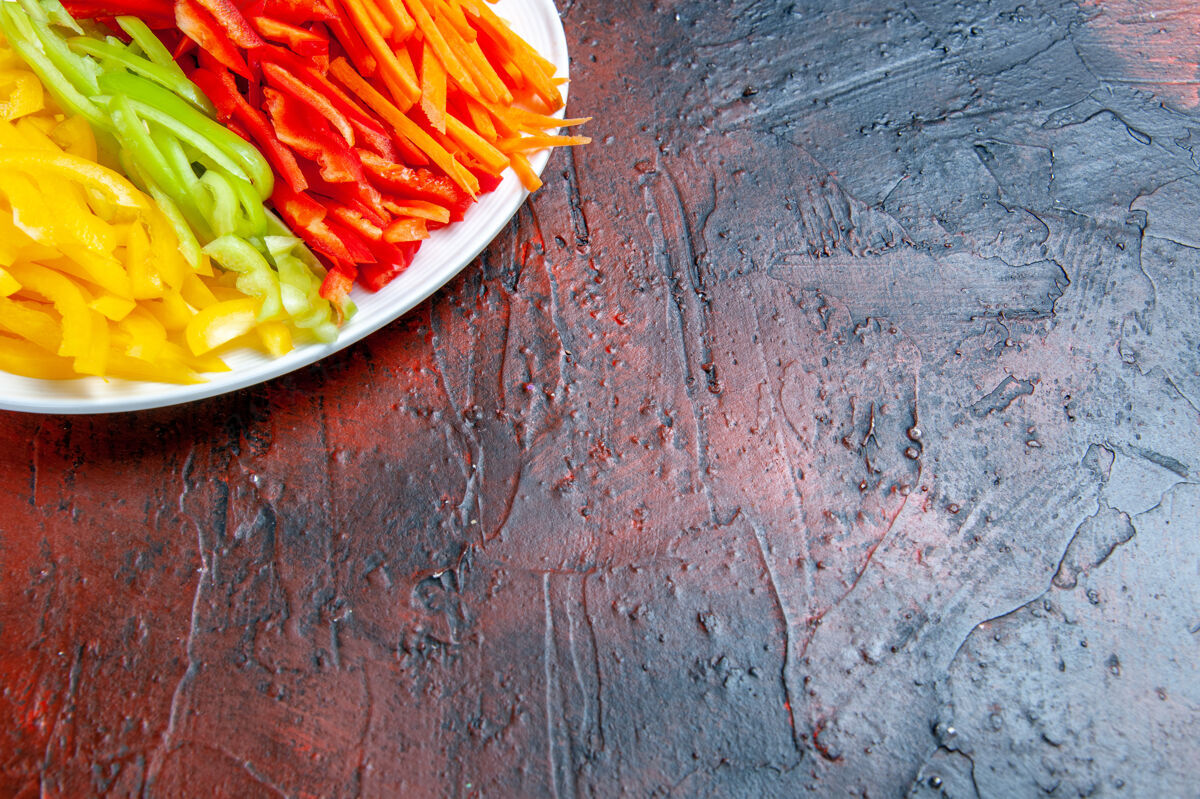 碗上半部分查看彩色切辣椒在白色盘子上的暗红色桌子与自由的地方辣椒午餐地方