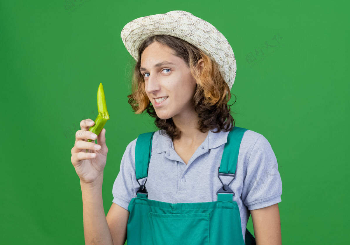 帽子年轻的园丁 穿着连体衣 戴着帽子 手里拿着一半的青椒半身年轻拿着