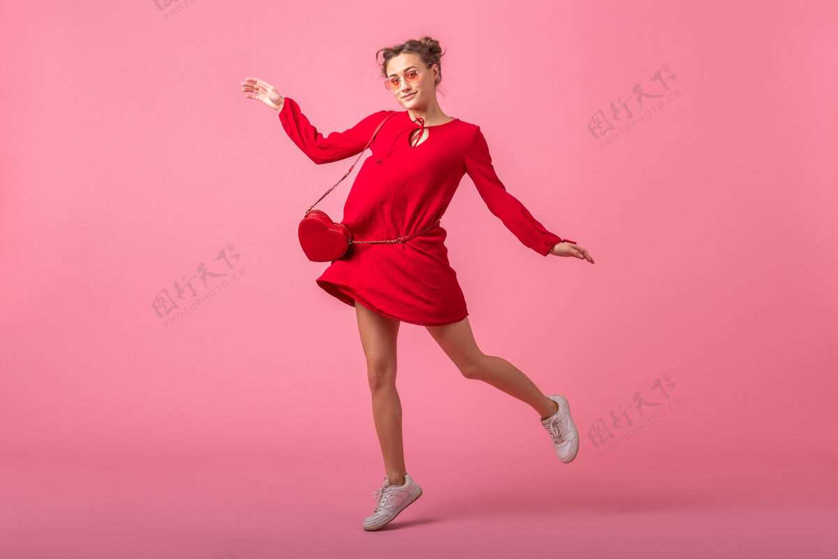 魅力迷人的快乐微笑的时尚女人穿着红色的时髦连衣裙在粉色的墙壁上跳跃奔跑孤立 春夏的时尚潮流 圣瓦伦尼特节 浪漫的心情调情的女孩女人天漂亮