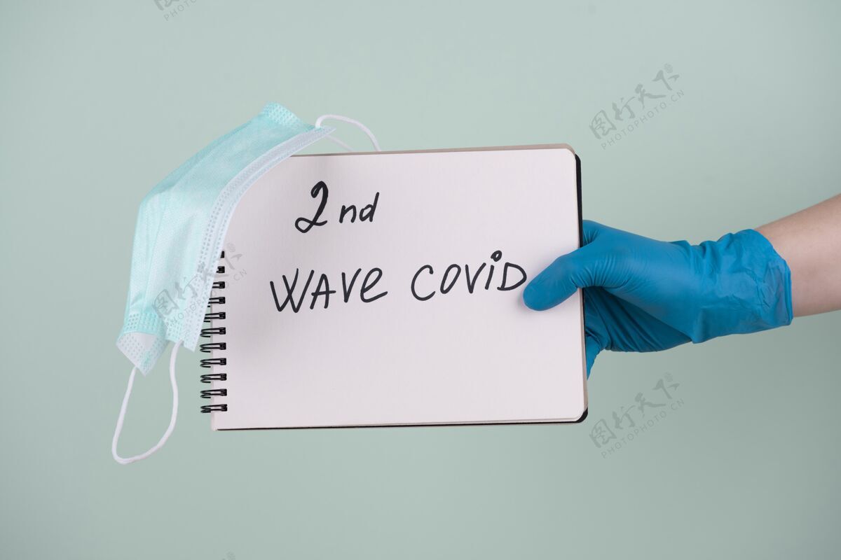 疾病戴着外科手套的手的正视图拿着笔记本 上面写着第二波covid前视图预防冠状病毒