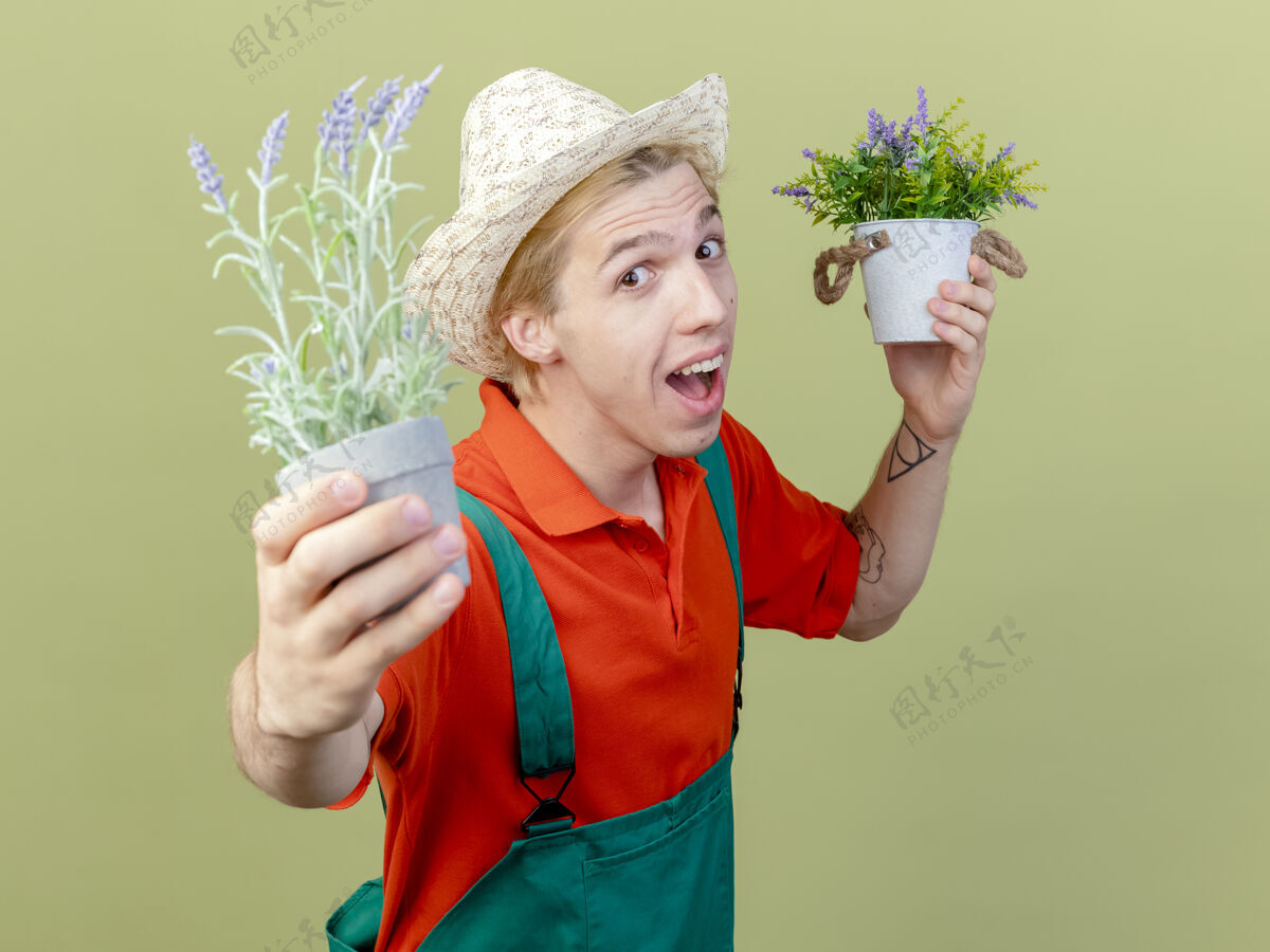 光年轻的园丁 穿着连体衣 戴着帽子 手里拿着盆栽植物微笑男人年轻