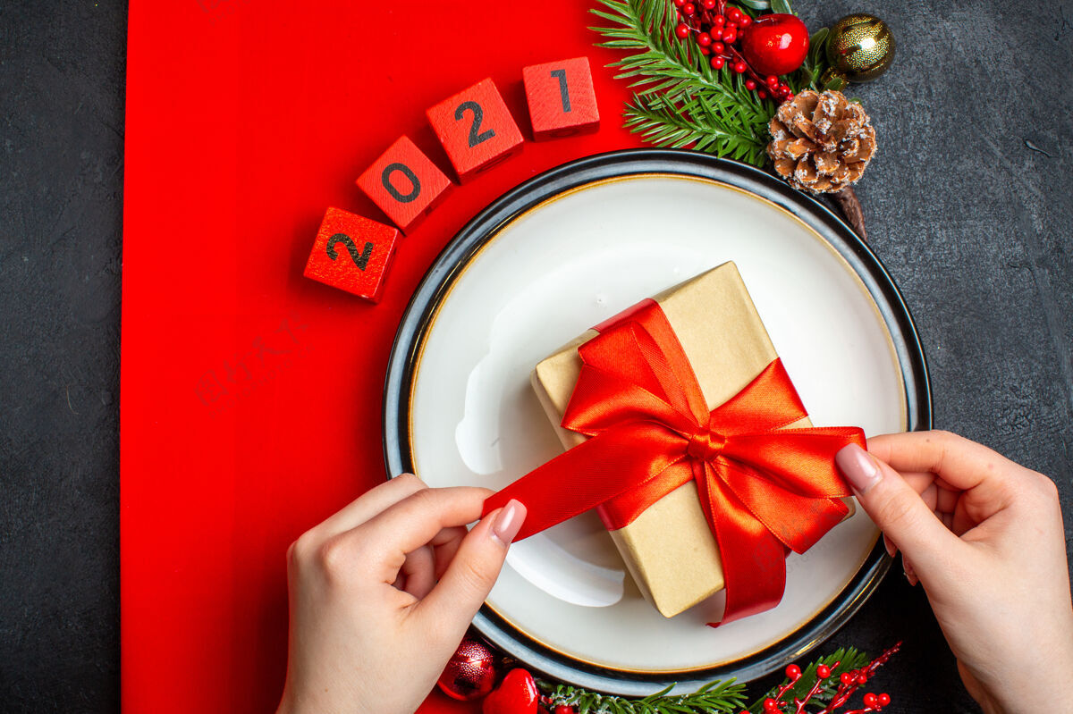 圣诞节新年背景俯视图 餐盘上有礼物装饰配件 黑色桌子上的红色餐巾上有杉木树枝和数字风景餐盘树枝