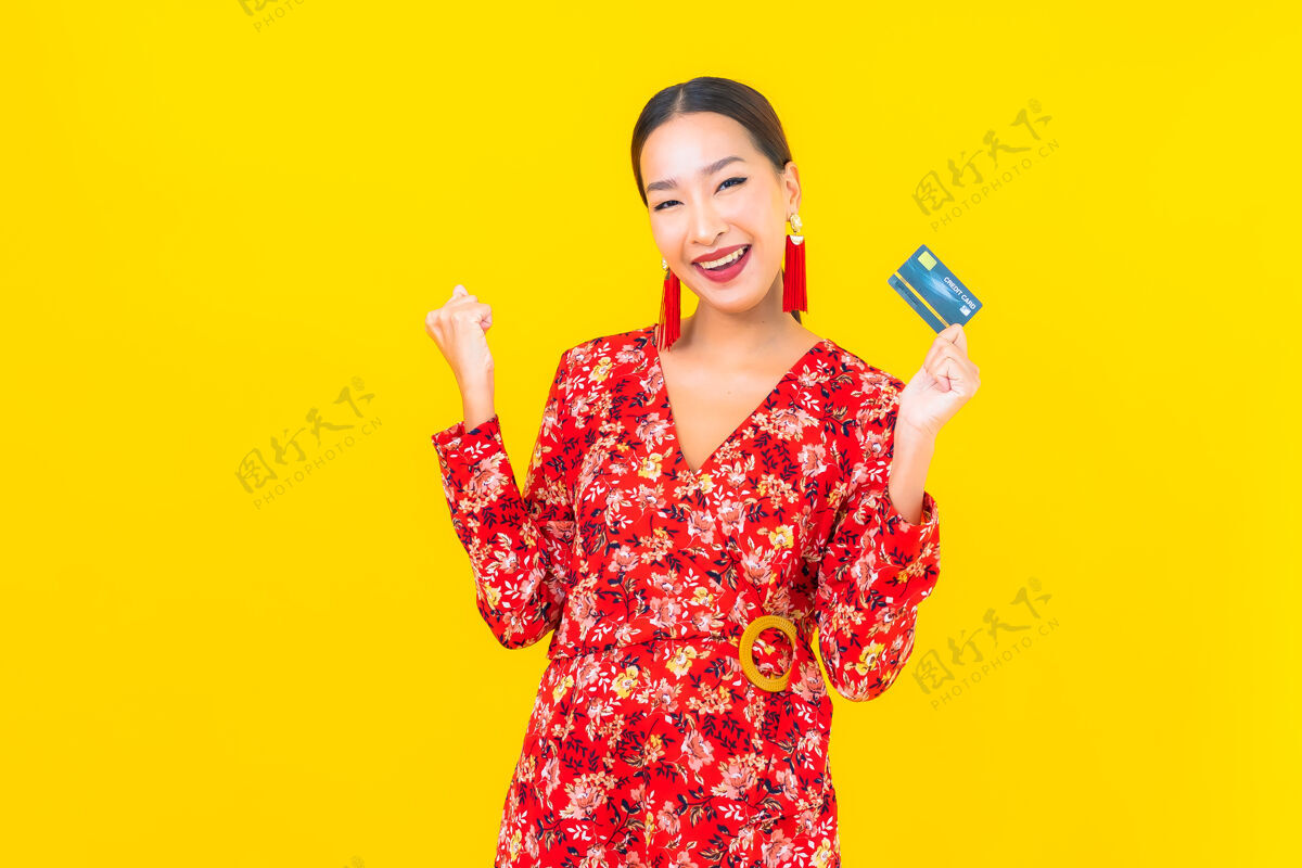 购买肖像美丽的亚洲年轻女子信用卡购物黄色隔离墙人女孩支付