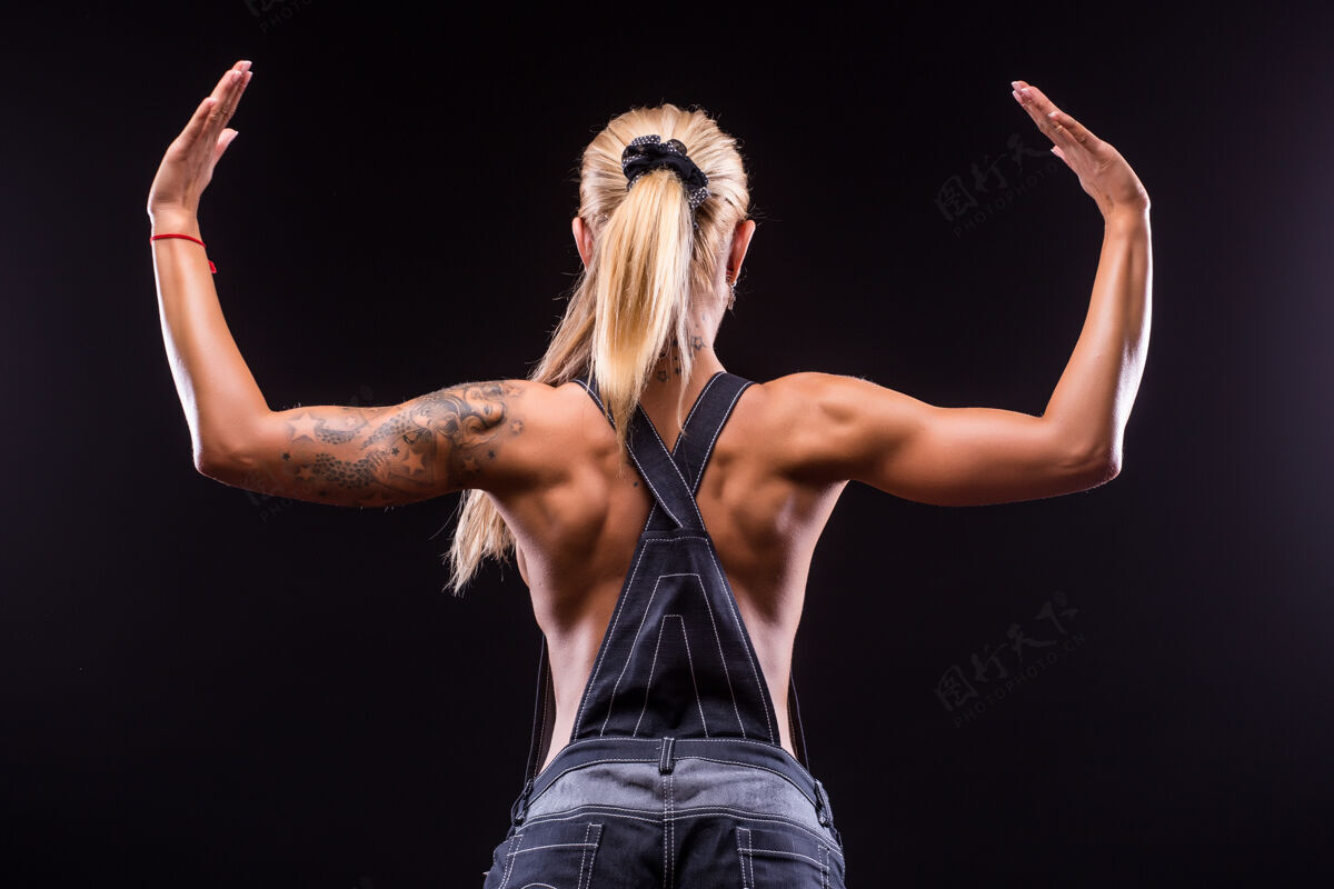 运动一个美丽的运动女子在黑暗中的肖像后视图私人教练体重训练