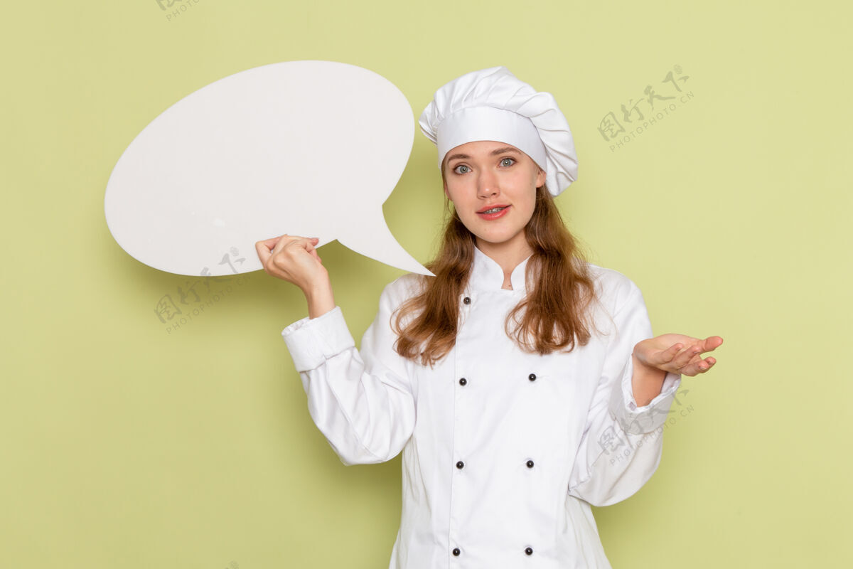 成人身穿白色厨师服的女厨师手持绿色墙上的大招牌的正视图西装淋浴帽护士