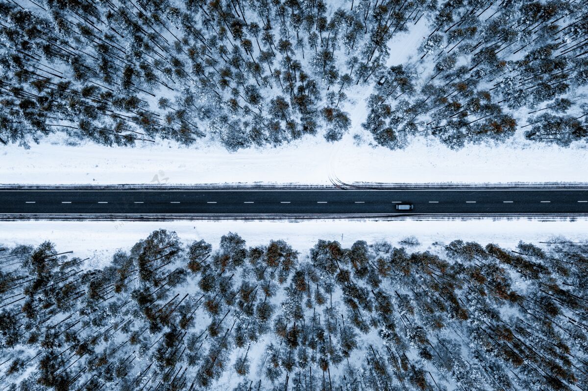 冰冻空中拍摄的道路在森林覆盖在冬天的雪背景季节场景