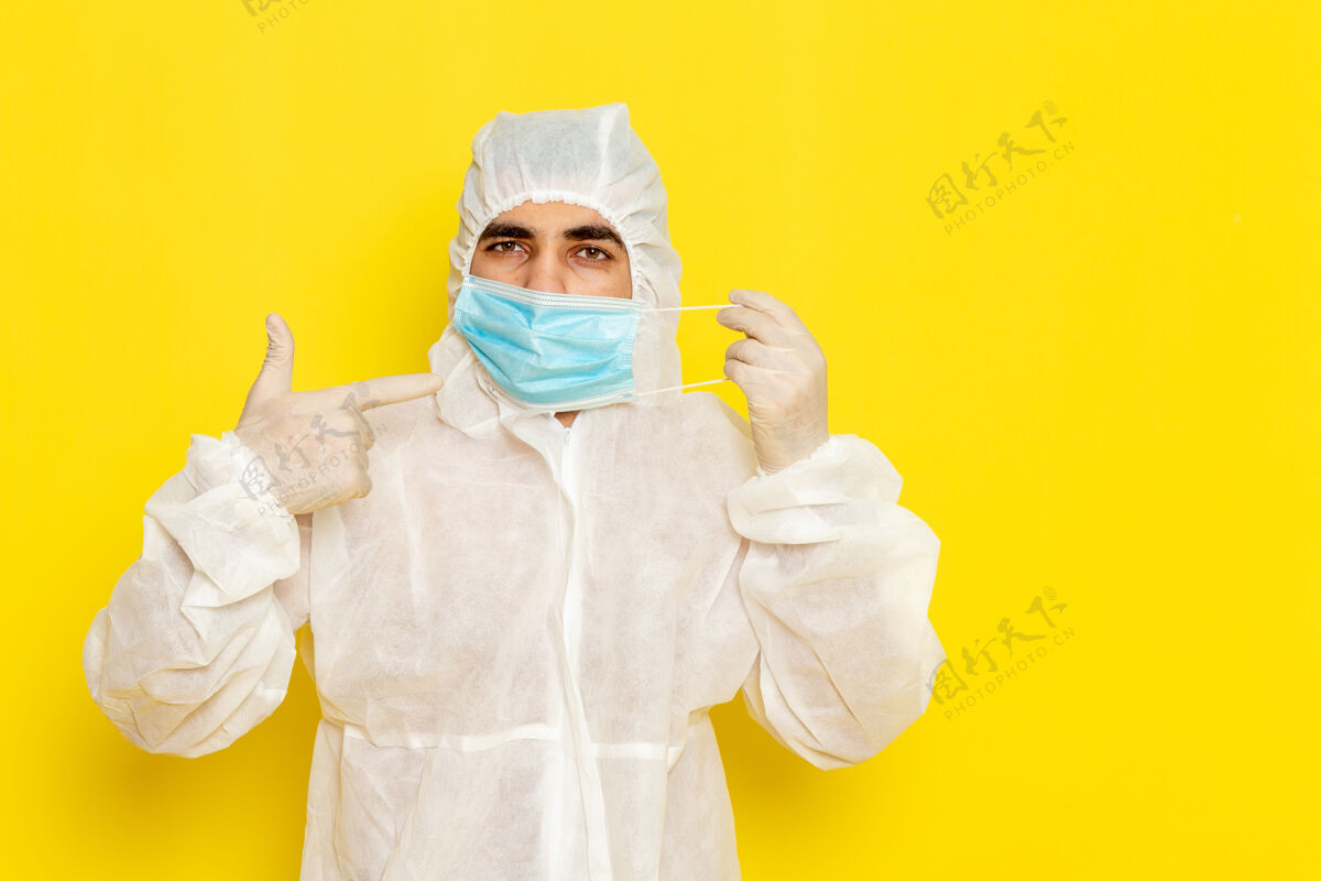 男性身穿特殊防护服的男科学工作者在淡黄色墙上摘下面具的正面图实验室外套正面科学