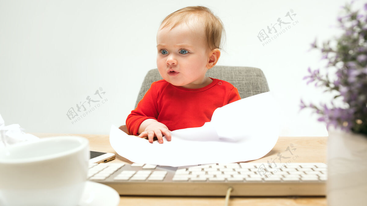 游戏小女孩坐在白色工作室里 用现代电脑或笔记本电脑的键盘年轻神奇老板