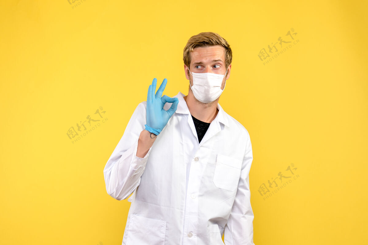 药品正面图黄色背景上的年轻男医生大流行医疗保健科维德-实验室专业人员实验室外套
