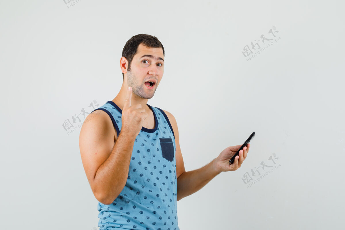 现代一个穿着蓝衫的年轻人手里拿着手机 指着脸好奇地看着电话向上衬衫
