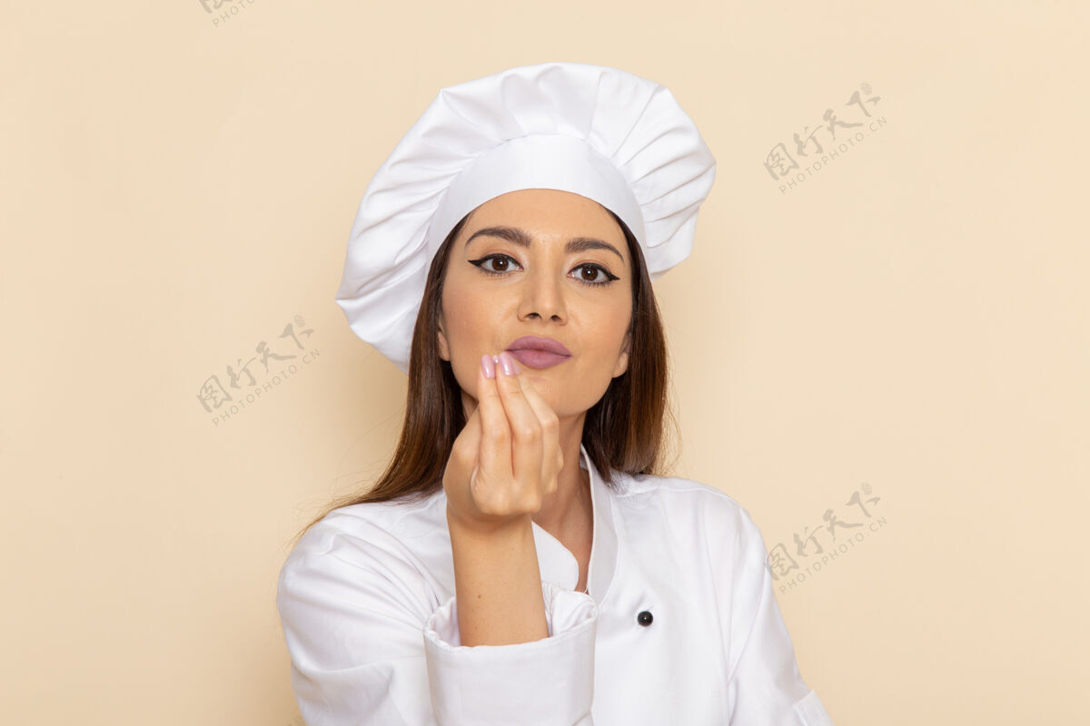 服装白色墙壁上穿着白色厨师服的年轻女厨师的正视图医生厨房烹饪