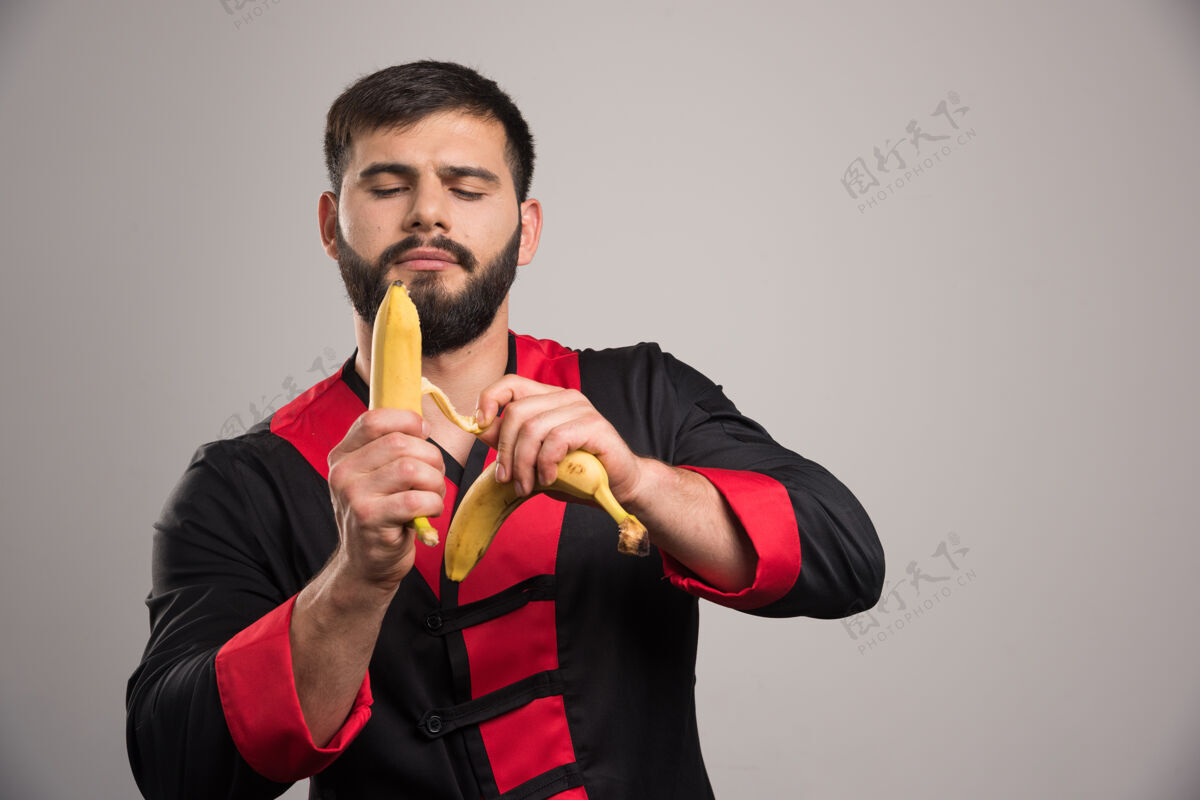 手年轻人在黑暗的墙上剥香蕉干净男人