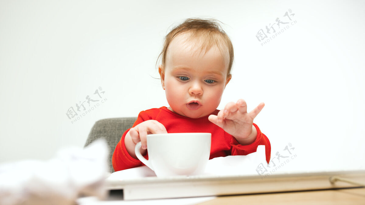 小我好累啊小女婴正坐在白色的现代电脑或笔记本电脑的键盘上有趣办公桌惊喜