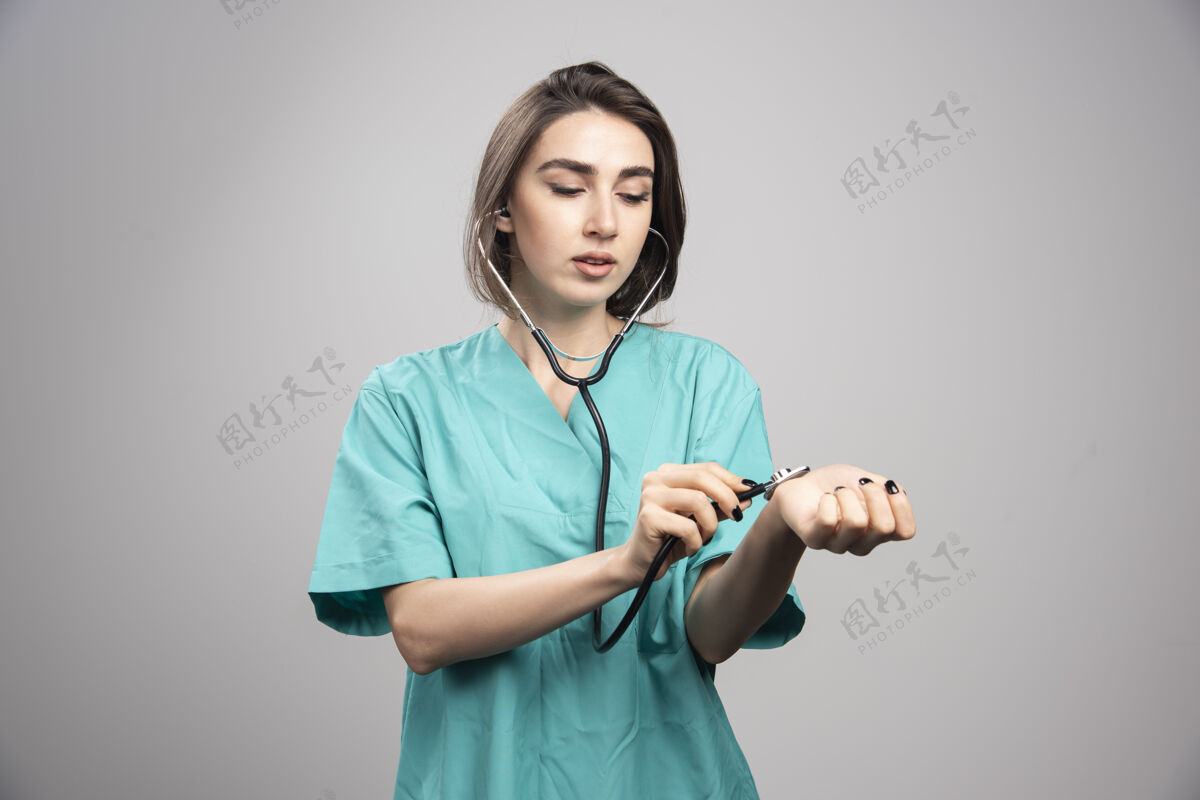 女性女医生用听诊器在灰色的墙上检查自己个人职业女性