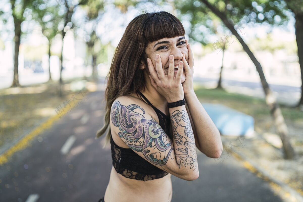 皮肤年轻迷人的白种女人站在公园里纹身 做一张可爱的脸女性手纹身