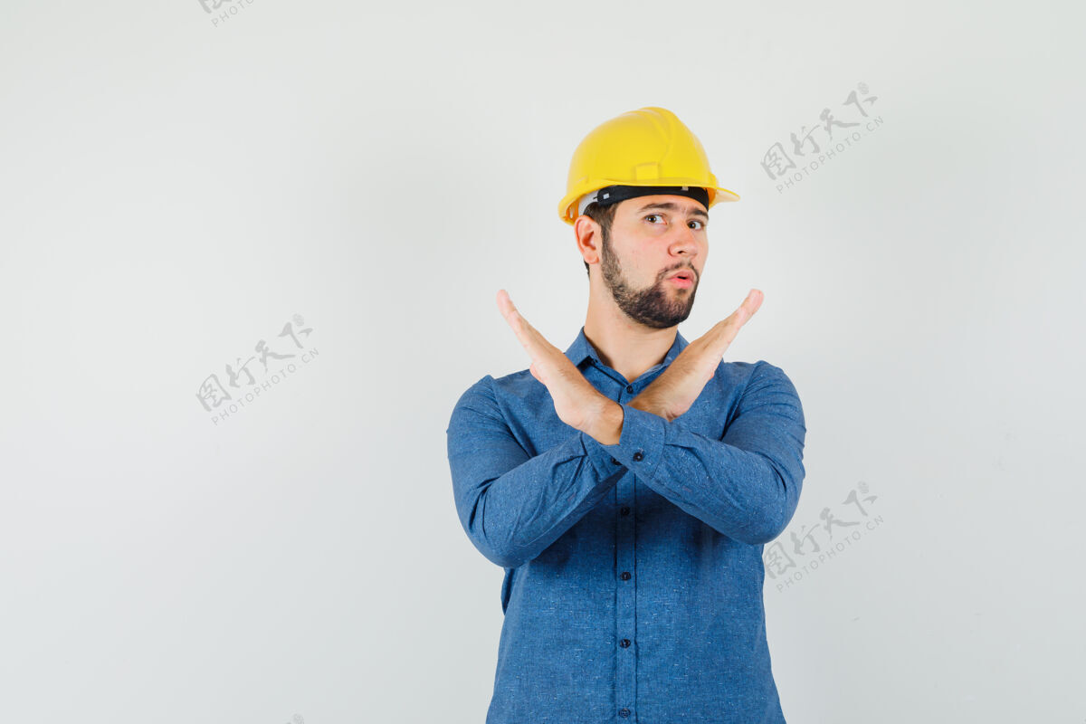 储存年轻工人穿着衬衫 戴着头盔 表情严肃 表现出拒绝的姿态劳动工作展示