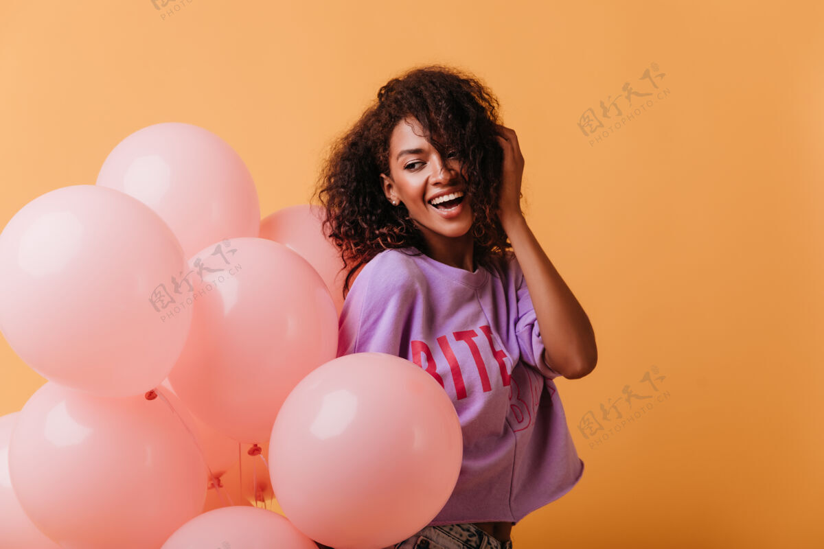 黑色无忧无虑的年轻女士手持氦气球在橙色和微笑笑积极的黑人女孩庆祝生日年轻肖像表情