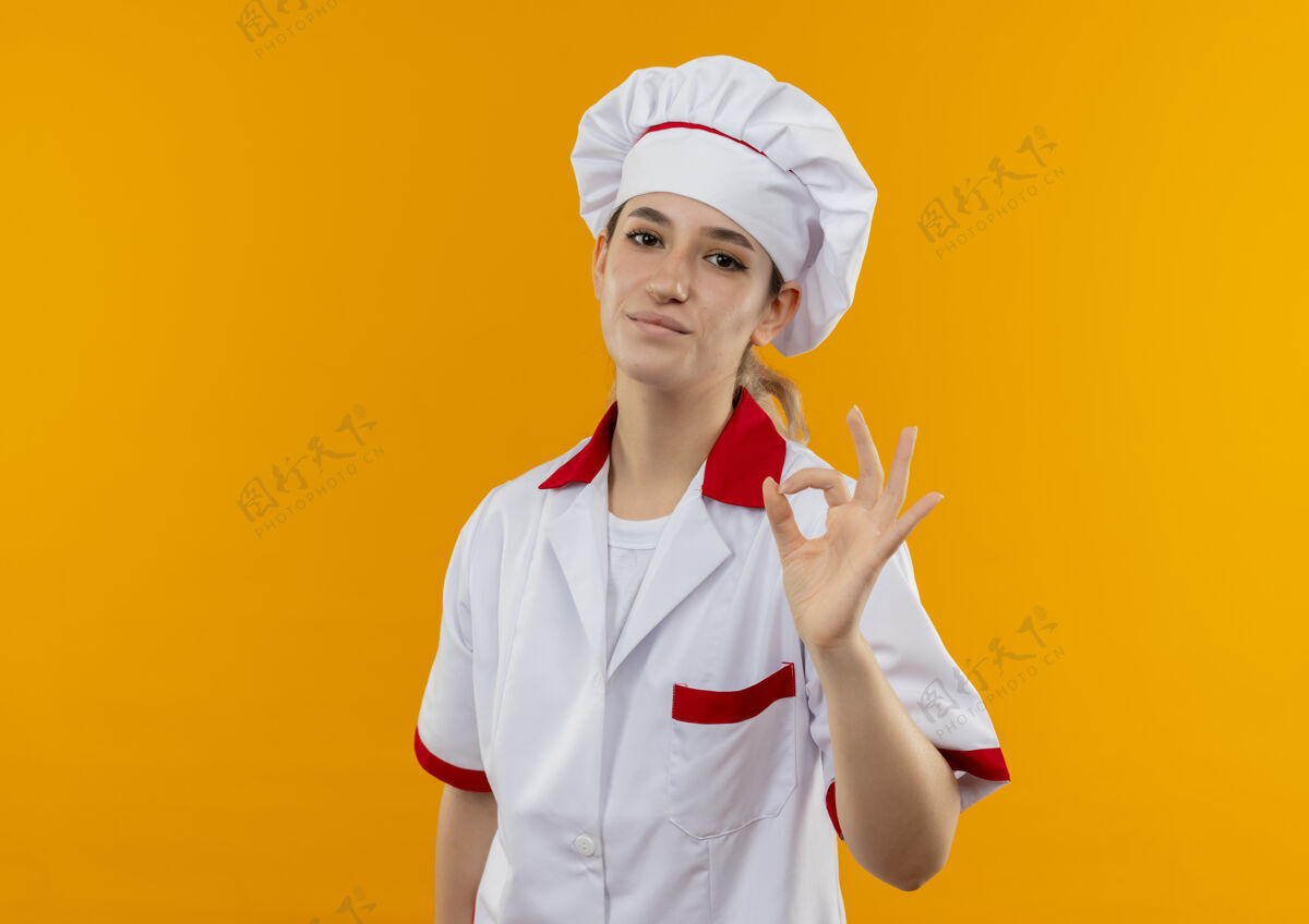 复制很高兴年轻漂亮的厨师穿着厨师制服 在橙色的空间里做着“ok”标志标志好漂亮