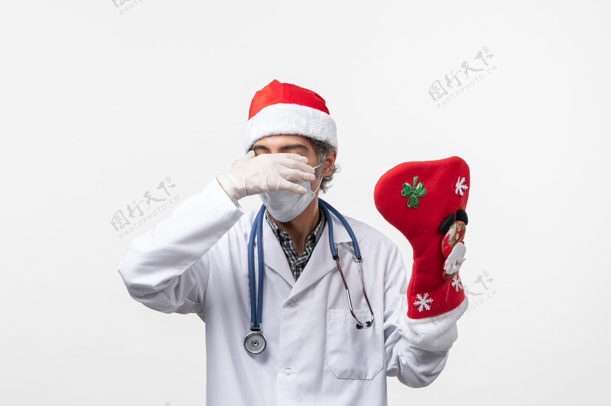 听诊器正面图男医生拿着白色墙壁上的大节日袜子病毒柯维德-节日冠状病毒大制服