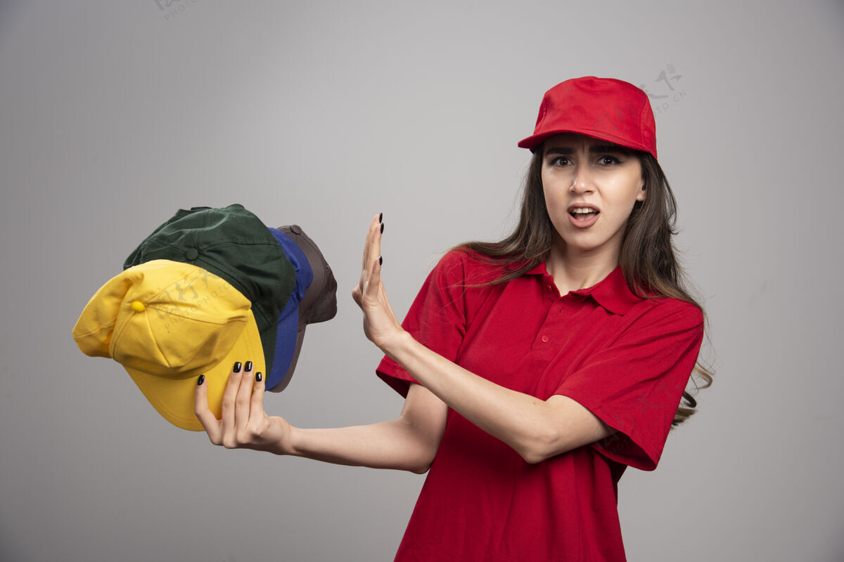 女穿红色制服的女送货员远离彩色帽子快递制服帽子