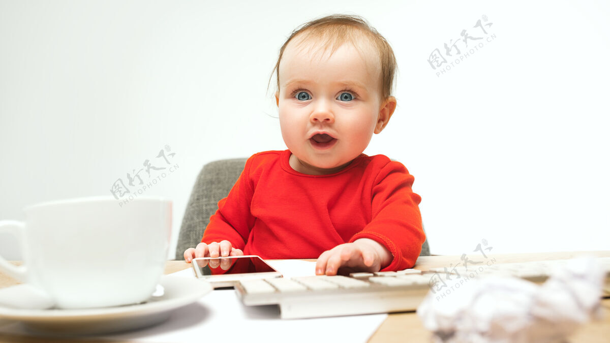 手机第一条短信小女婴坐在键盘的现代电脑或笔记本电脑在白色老板小搞笑