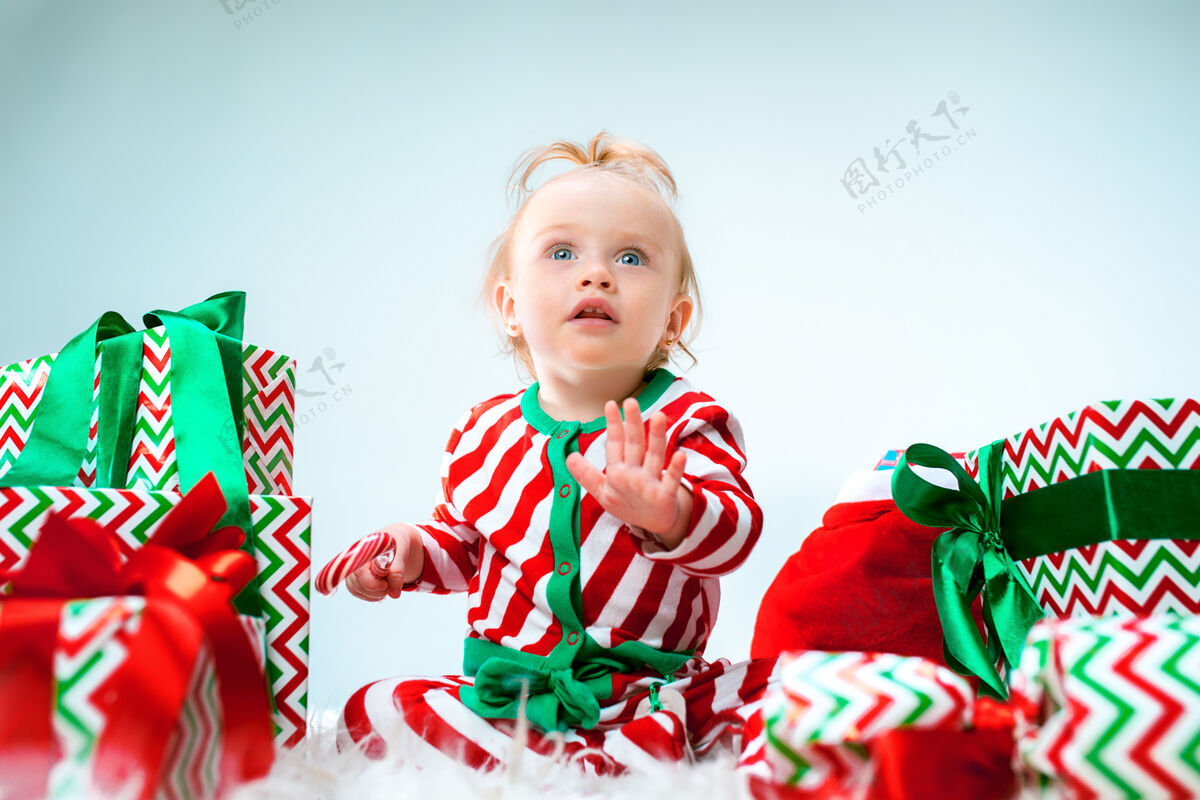 小可爱的女婴 1岁 戴着圣诞帽 带着圣诞装饰 坐在地上玩圣诞球现代圣诞节帽子