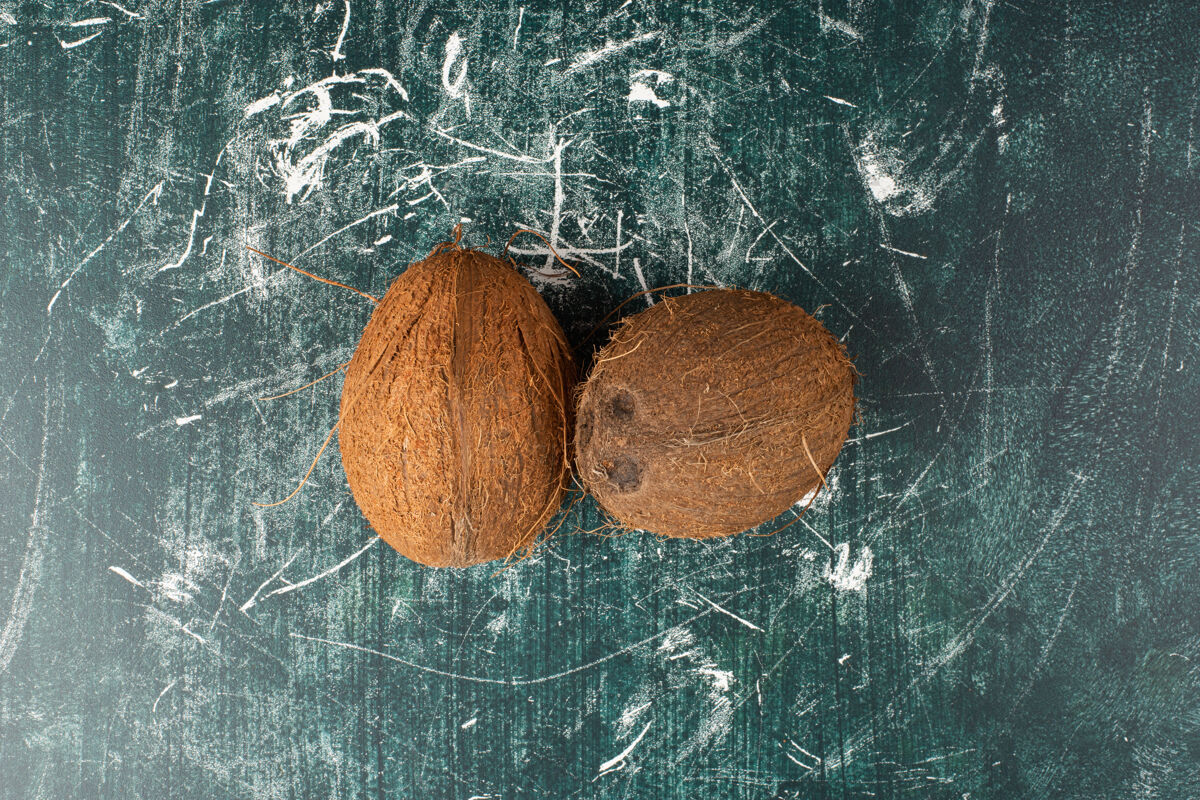 整个两个完整的椰子放在大理石表面热带顶视图棕色