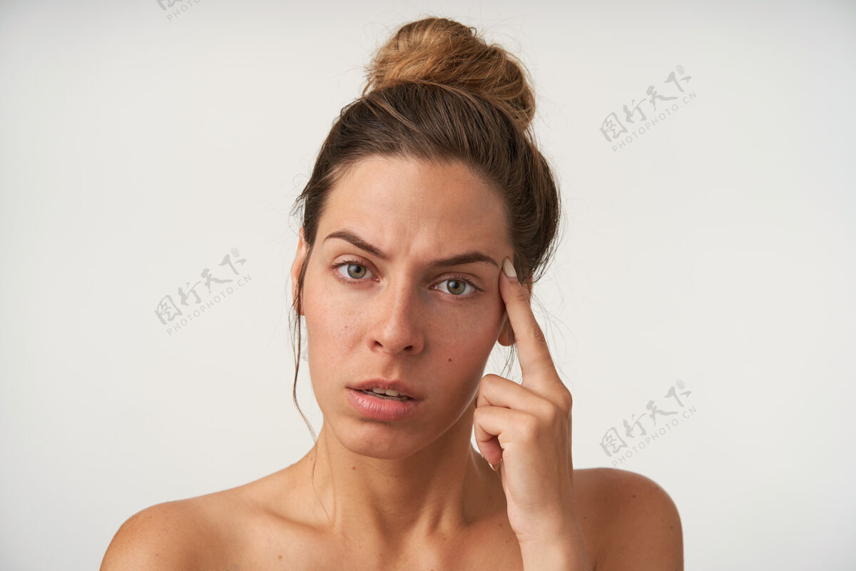 女士室内写真 疲惫的年轻女子 随意的发型 皱着眉头 把食指放在太阳穴上 孤立在白色上肖像脸年轻
