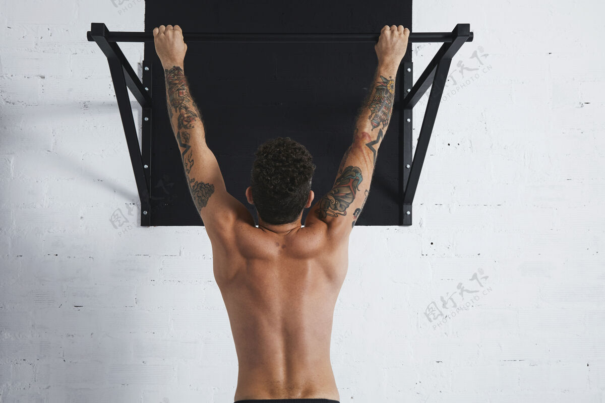 训练背视图肌肉赤裸上身的男运动员显示健美操动作挂在撑杆上锻炼活动运动