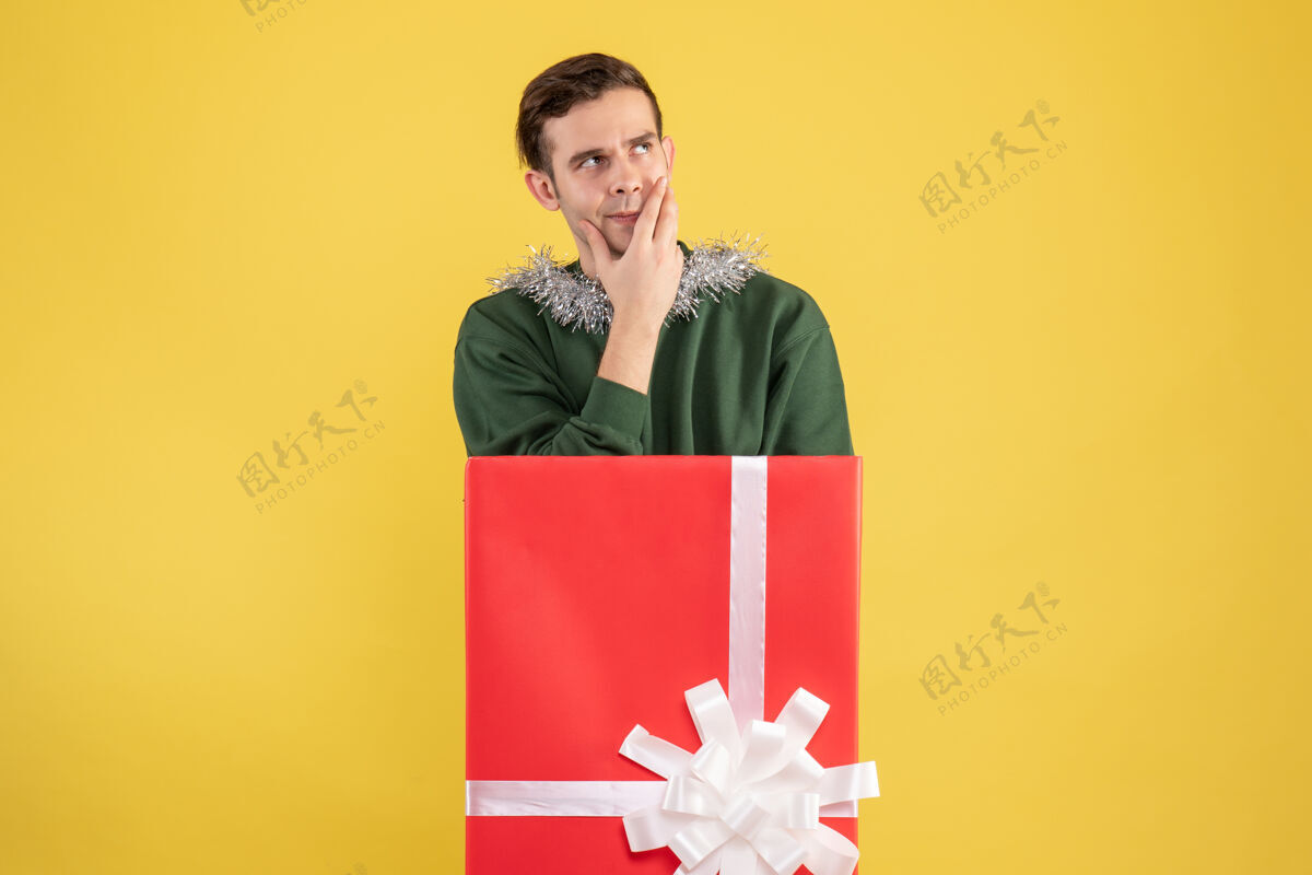 微笑正面图：体贴的年轻人站在黄色的大礼品盒后面男人成年人大