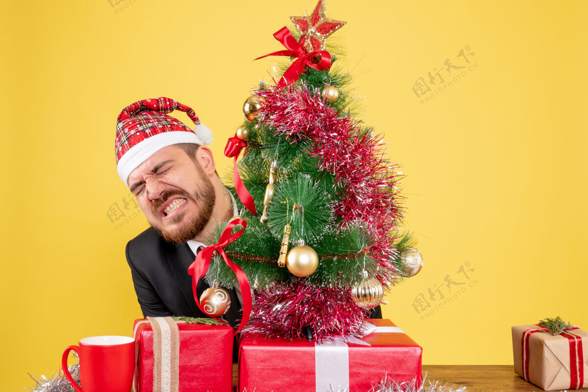坐正面图男性工人坐在他工作的地方后面 黄色的是礼物庆祝圣诞节树