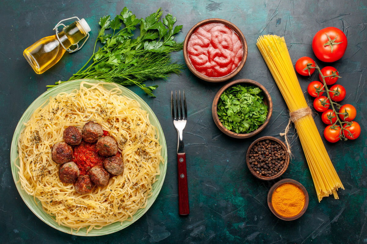 盘子在深蓝色的桌子上俯瞰美味的意大利面食 有肉丸和不同的调味品午餐食物餐