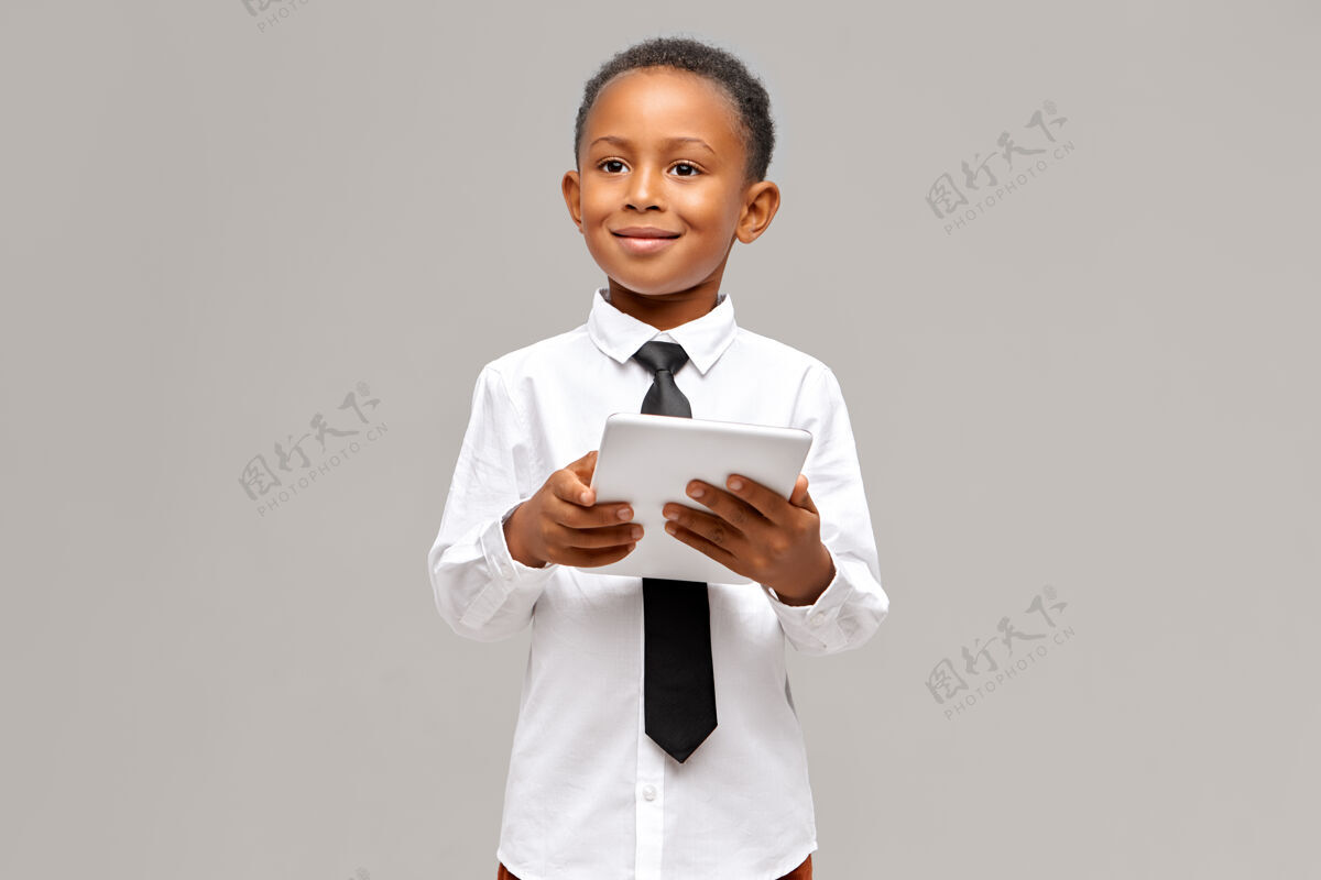 休闲儿童 电子设备和小玩意的概念聪明自信的非洲学生在制服摆姿势与便携式触摸板电脑在他手中 上网或网上购物游戏英俊学习