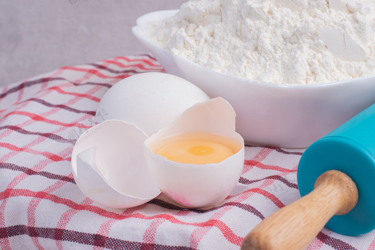 鸡蛋碎鸡蛋 擀面杖和一碗面粉放在桌布上料理碎大头针