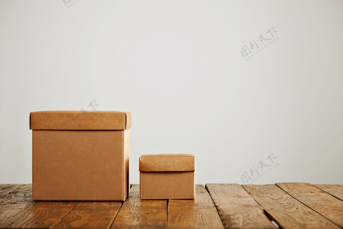 商品新的不同大小的米色纸板箱与覆盖对比老粗糙的木桌在一个白色墙壁的工作室包装打开包装