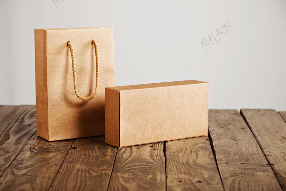 木材工艺纸袋和纸板空白盒呈现在质朴的木桌上 隔离在白色背景上包裹包装搬运