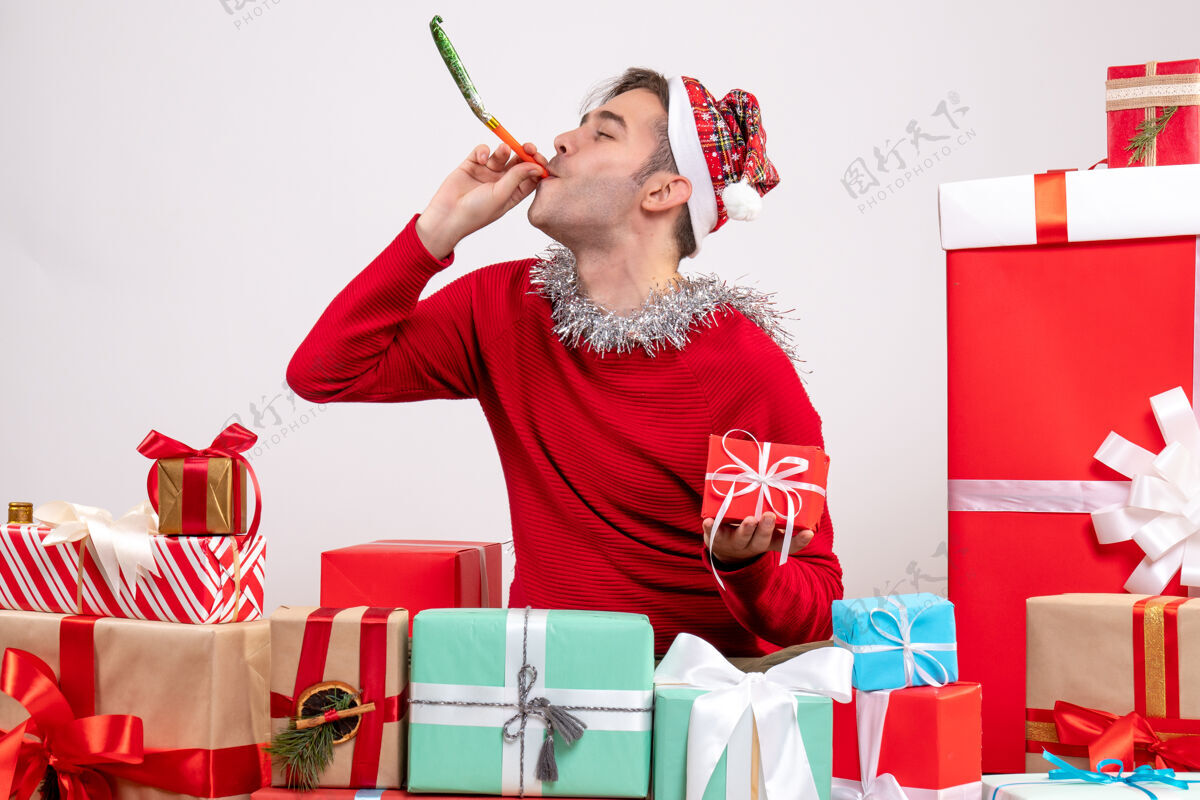 坐着前视图年轻人使用隔音器围坐在圣诞节礼物购物年轻人噪音制造者