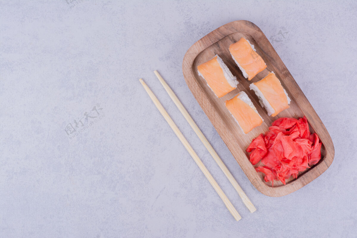 传统三文鱼卷放在木盘里和腌姜一起食品质量筷子