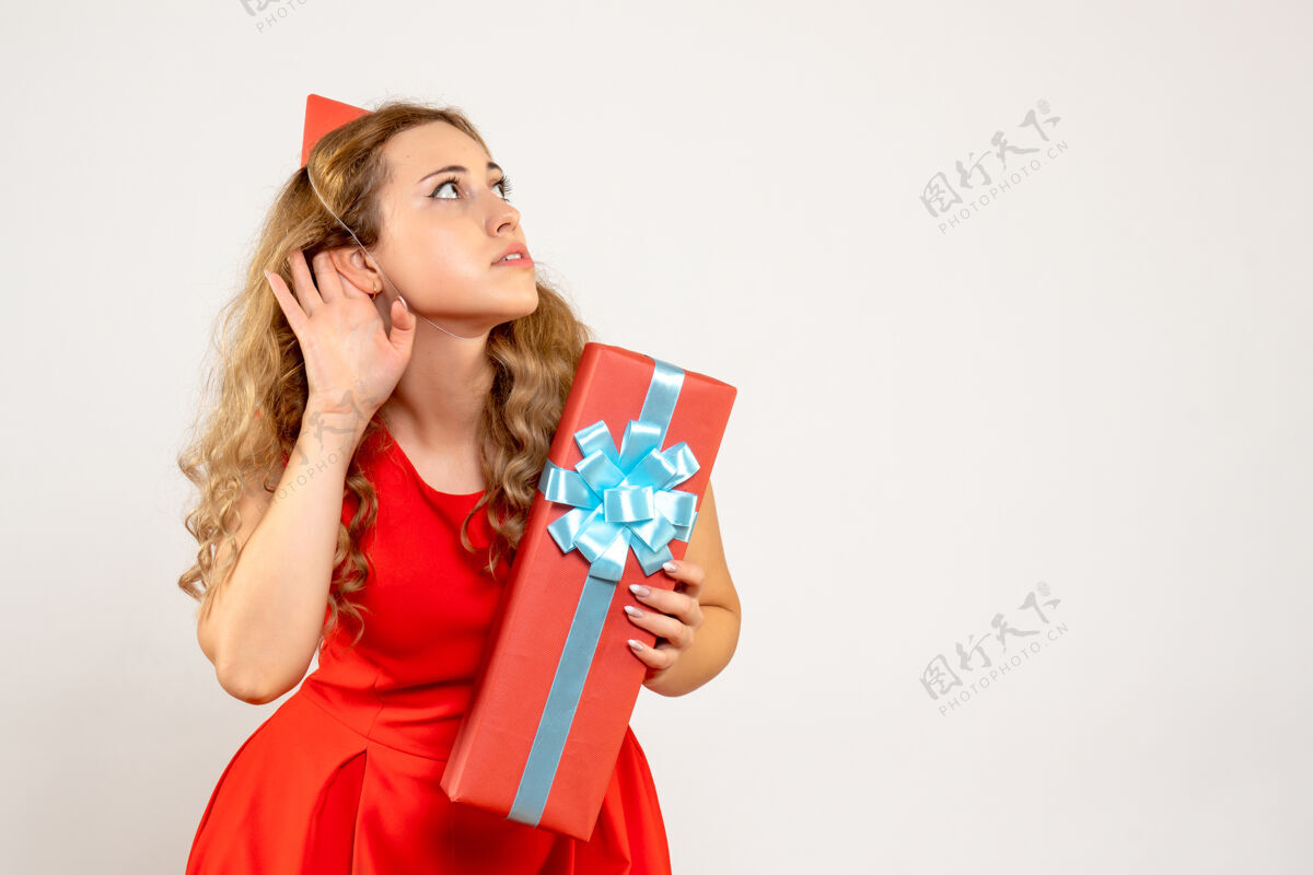 颜色正面图身着红色连衣裙的年轻女性用礼物庆祝圣诞节衣服礼物圣诞节