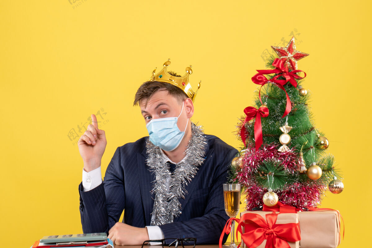 人前视图的商人与皇冠坐在桌旁圣诞树和黄色的礼物桌子皇冠坐