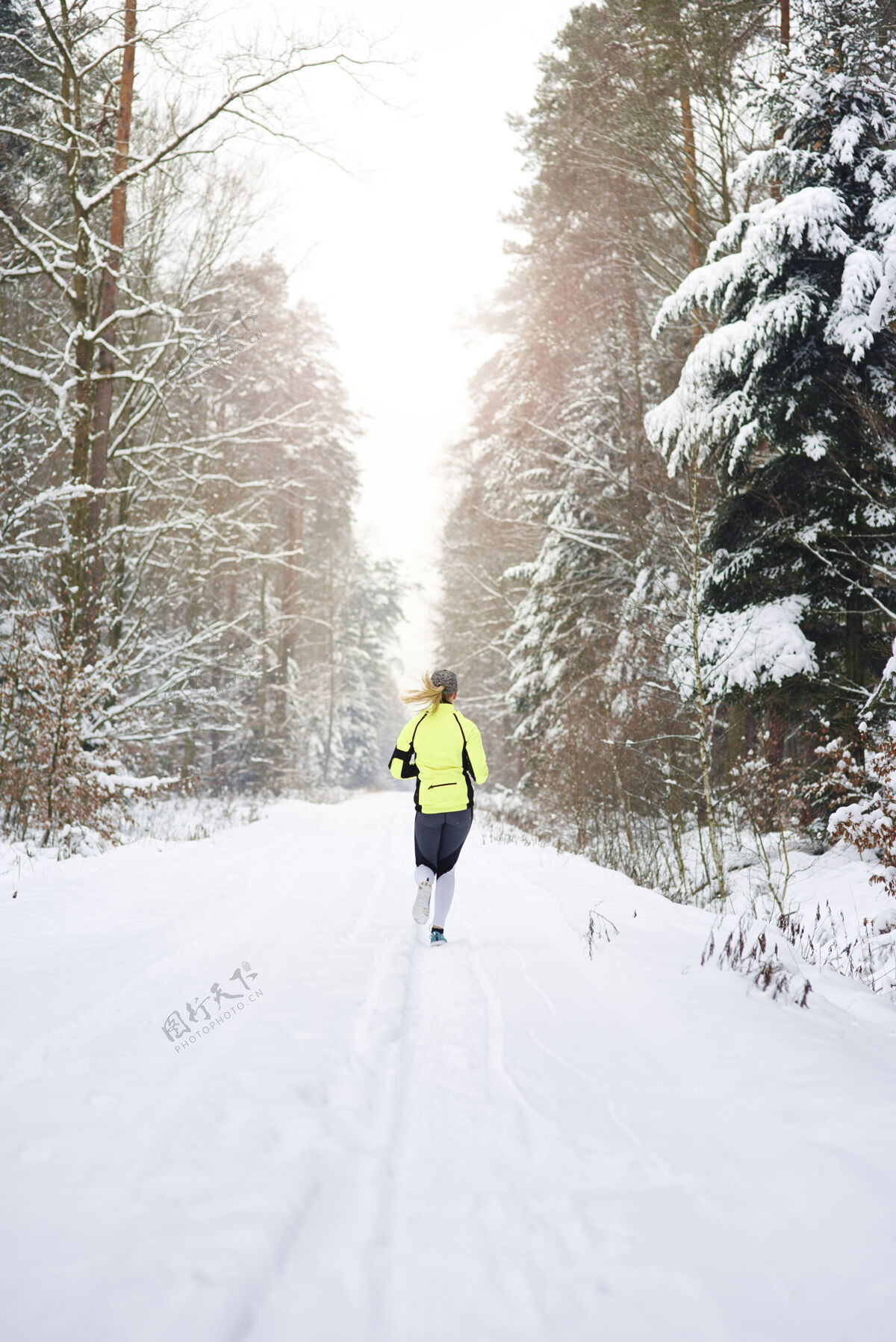 后方在冬天森林里奔跑的女人的后视图运动员健康生活方式专业