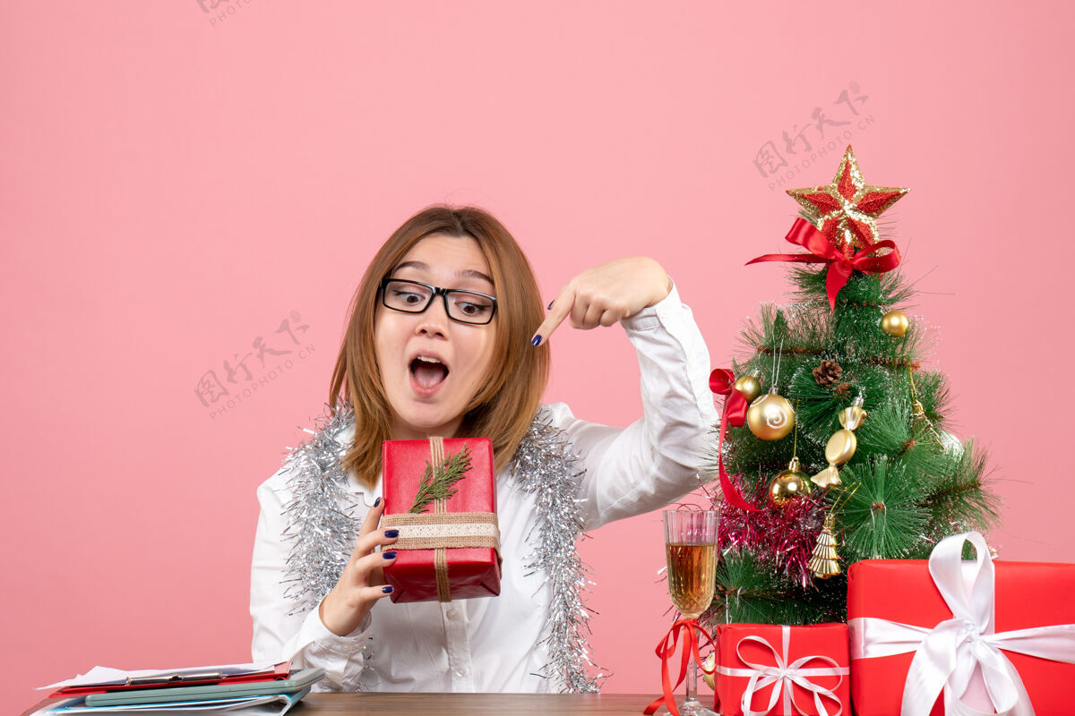肖像女工正坐在粉红色的椅子上 手里拿着圣诞礼物坐着工人工作