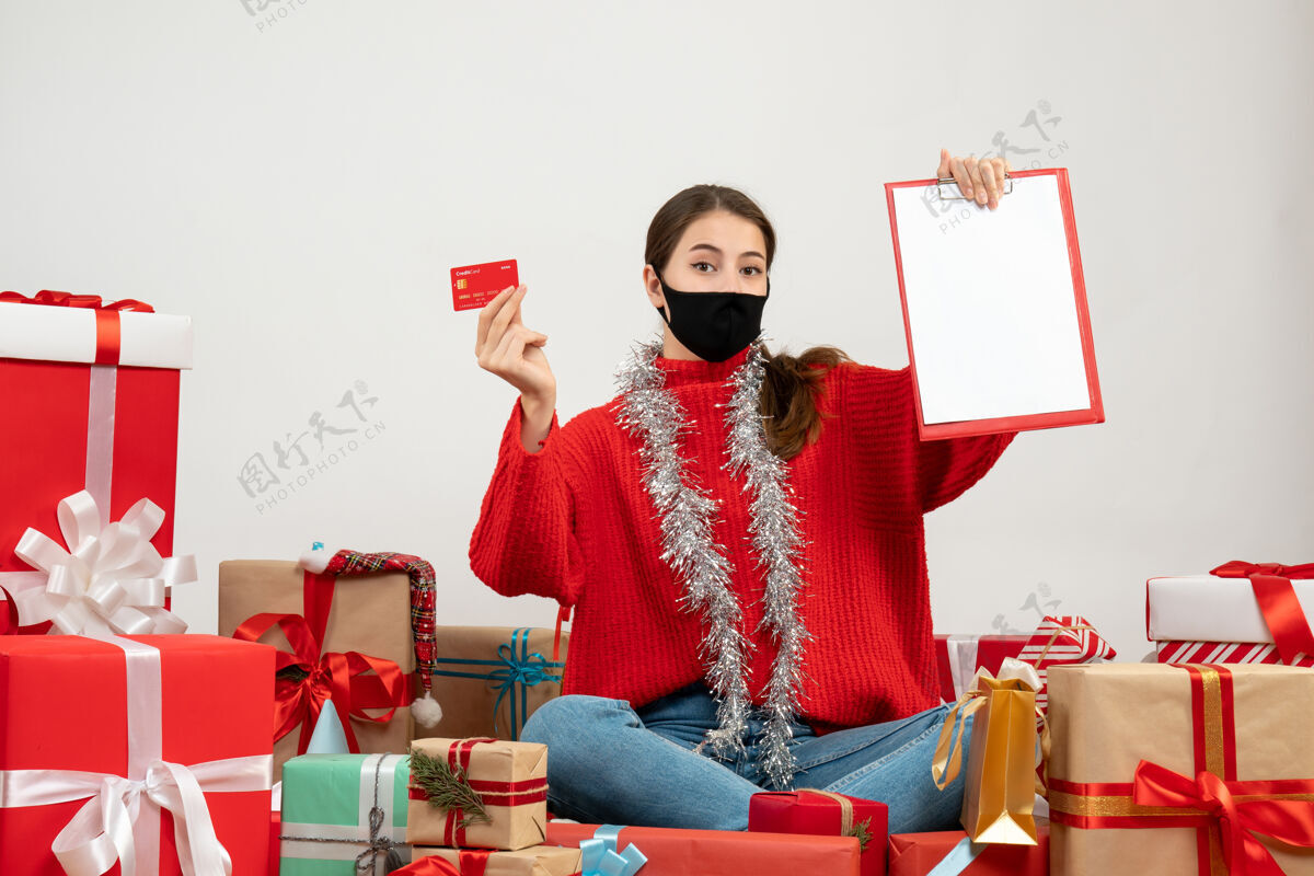 庆祝戴着黑色面具的年轻女孩拿着卡片和文件围坐在白色的礼物上礼物礼物购物