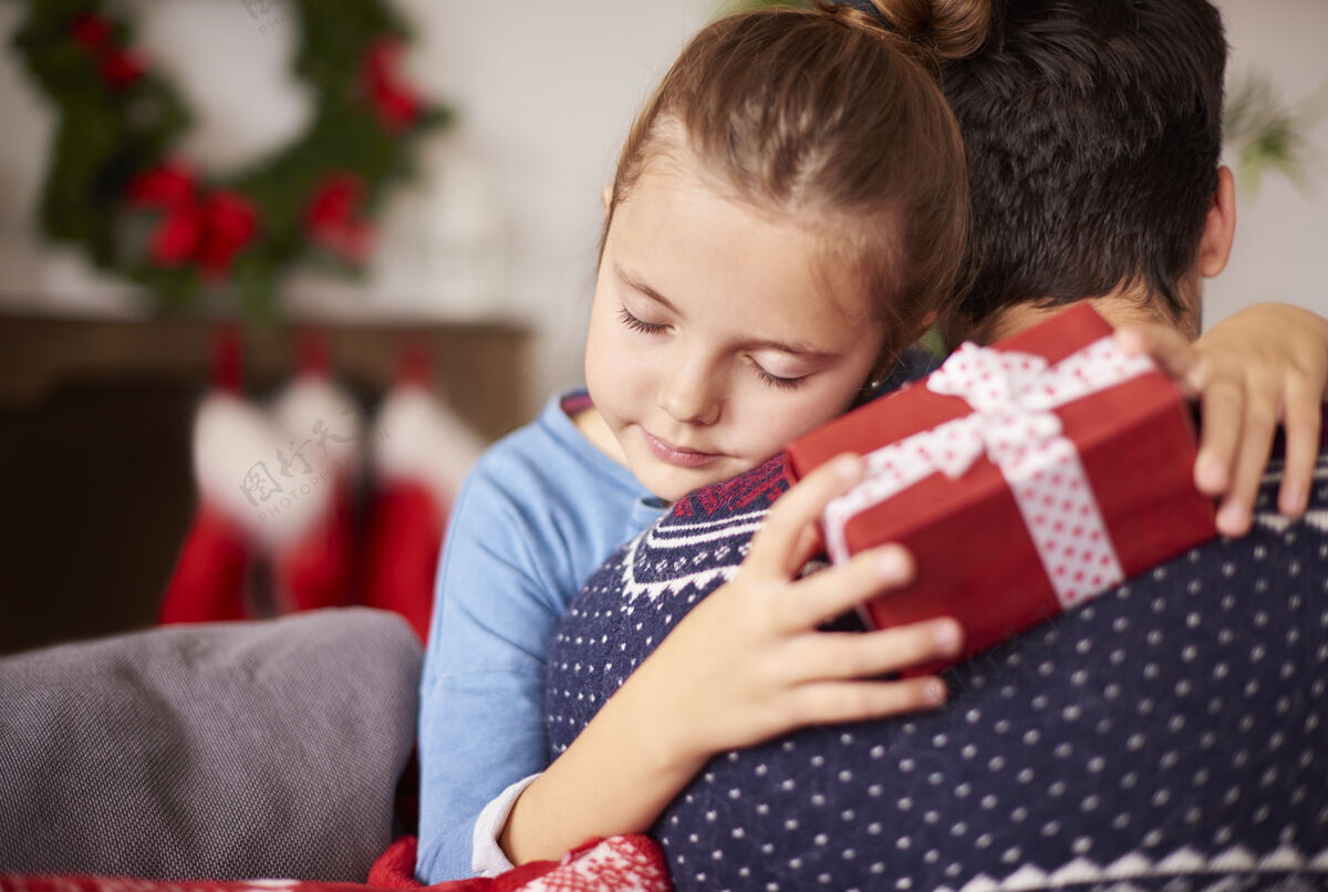 圣诞老人小女孩在圣诞节拥抱她的爸爸关闭粘合圣诞装饰品