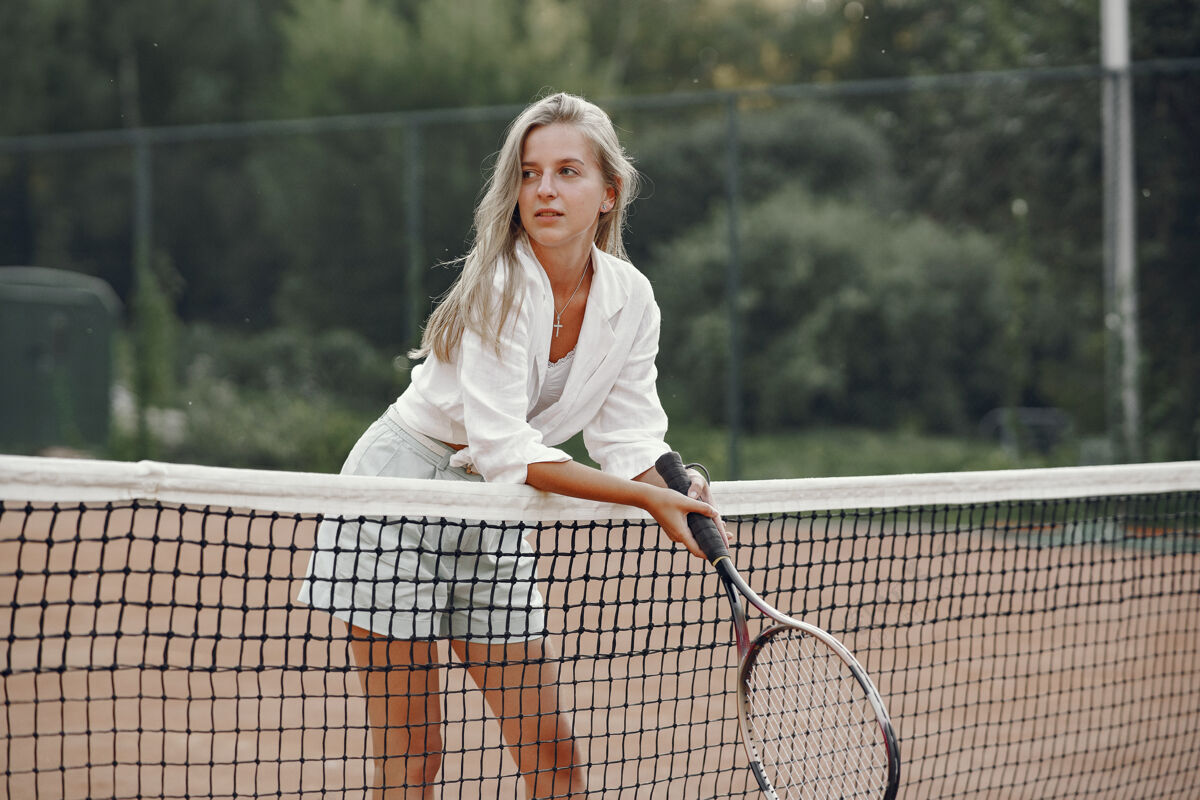 看今天玩得很开心 穿着t恤的年轻女子拿着网球拍和球的女子户外球运动员