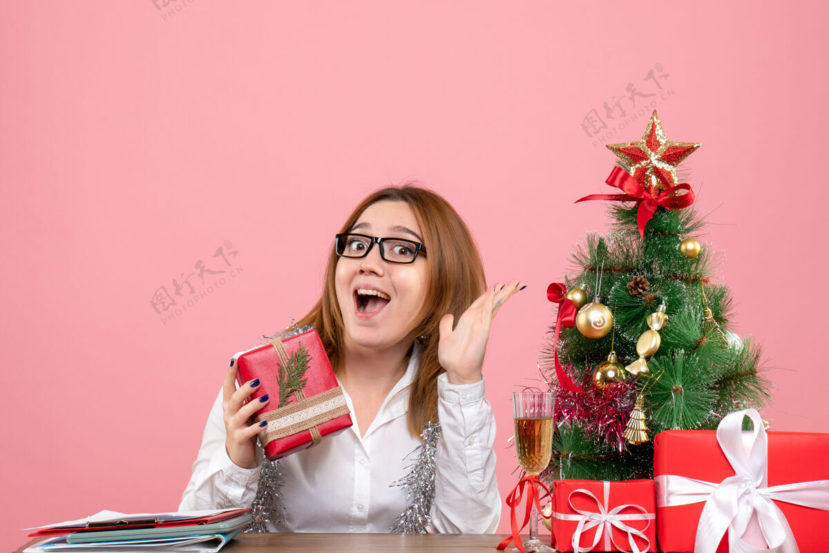 女工人女工围坐在粉红色的圣诞礼物和圣诞树旁的正视图女办公室礼物
