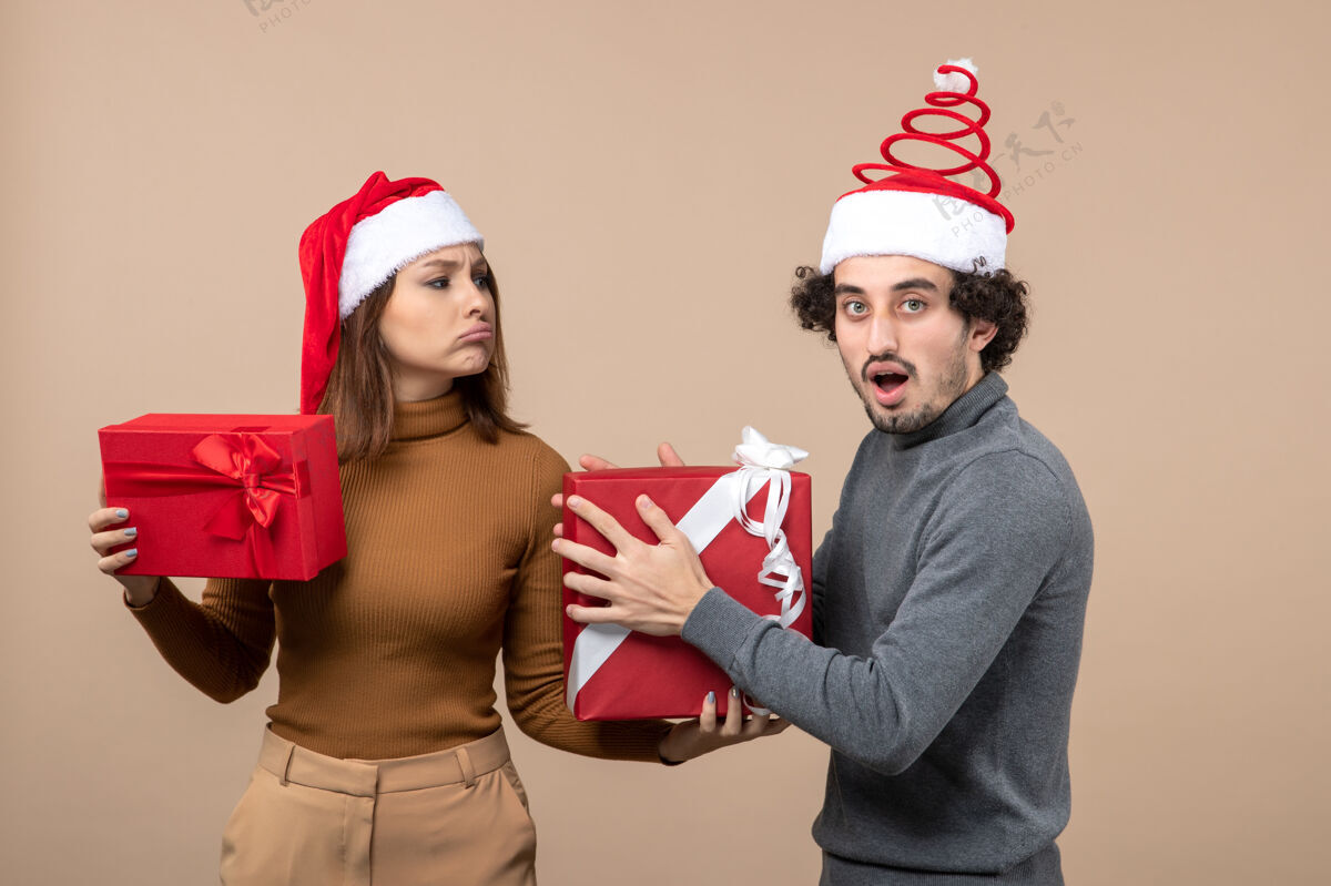 心情新年气氛喜庆的概念与搞笑酷可爱的情侣穿着灰色的红色圣诞老人帽可爱可爱的情侣帽子