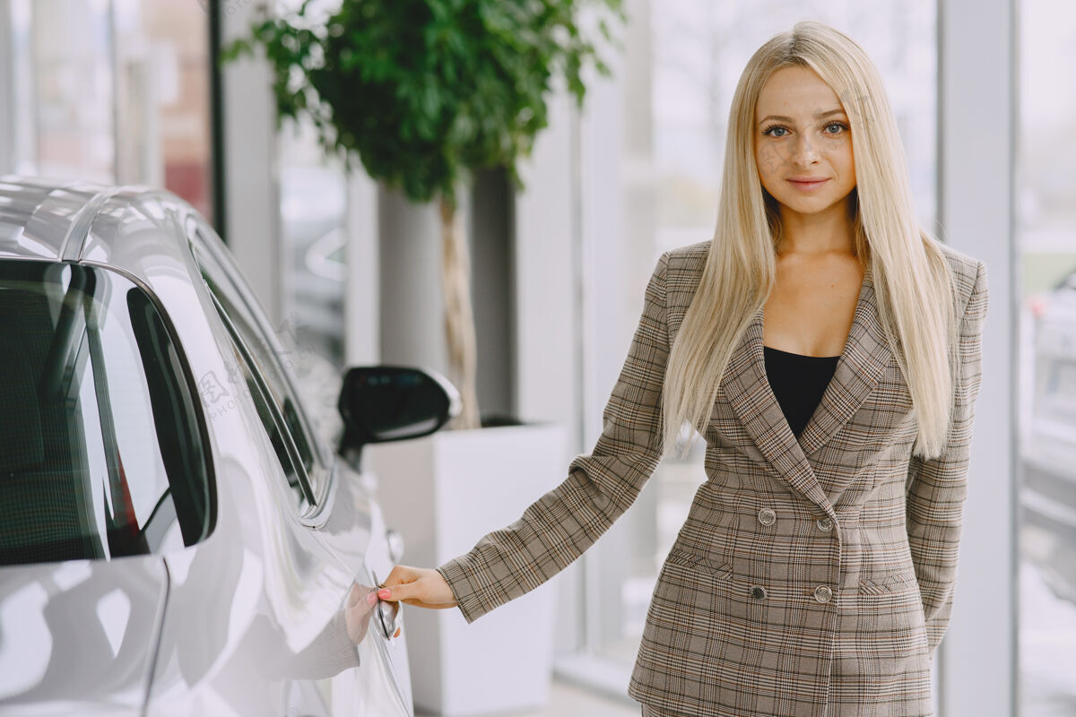 服装汽车沙龙里的女士买车的女士穿着棕色西装的优雅女士零售金发驾驶